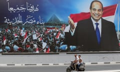 People ride a motorcycle past an election campaign banner erected by supporters of Egyptian President Abdel Fattah al-Sisi in Cairo, Egypt.