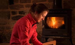 A woman reading a book in front of a wood-burning stove