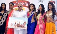 (FILES) This file photograph taken on December 21, 2013, shows Indian UB Group chairman Vijay Mallya (C, in white) as he poses with models during the launch of the Kingfisher 2014 calendar in Mumbai. An Indian court on April 18, 2016, has issued an arrest warrant for the embattled tycoon Vijay Mallya, who left the country owing more than USD1 billion, an official told AFP. The 60-year-old liquor baron, once dubbed the King of Good Times, left India on March 2, despite calls for his arrest and is believed to be in Britain. / AFP PHOTO / STRSTR/AFP/Getty Images