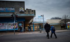 A mother and young boy walk hand-in-hand towards the front of the dilapidated Strand shopping centre in Bootle.