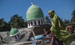 A Muslim woman walks past a mosque collapsed