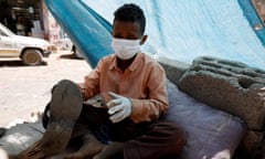 A child shoemaker wears a face mask and gloves to protect against Covid in Sanaa, Yemen