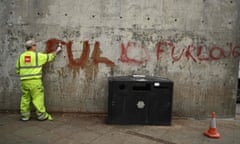 A worker cleans graffiti calling for ‘full furlough’ in Piccadilly Gardens, central Manchester