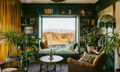 Window seat in the living room, with old leather armchairs, potted ferns and a floor lamp with a fringe, looking onto bare trees outside