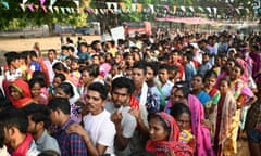 Separate lines of Indian men and women queueing under lines of bunting