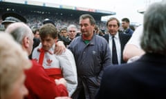 Nottingham Forest manager Brian Clough, centre, and Liverpool manager Kenny Dalglish, left, leave the pitch at Hillsborough stadium on 15 April 1989 after the disaster that killed 97 people.