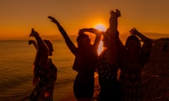 Young friends dancing on a beach at sunset