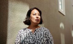 Woman wearing black and white patterned shirt in front of beige wall looks to the right