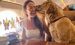 Woman with champagne on private jet being nuzzled by dog.