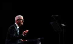 man in a suit giving speech on a stage