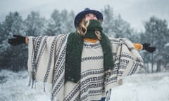 Woman raising hands, enjoying in cold snowy winter day, wearing woven poncho.