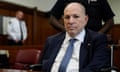 Man with shaved head and suit sits in court in wheelchair