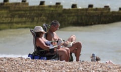 Holidaymakers reading on Eastbourne beach, East Sussex.