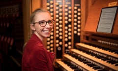 Anna Lapwood seated at an organ, looking to her right and smiling