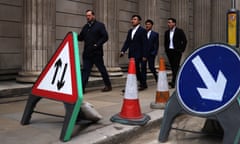 People pass signs outside the Bank of England in London.