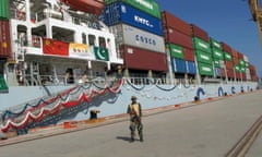 A Pakistan navy soldier stands guard while a loaded Chinese ship prepares to depart from Gwadar.