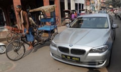 Rickshaws and a new BMW drive through the old town of Old Delhi, India