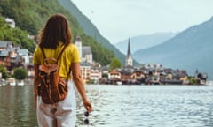 Woman stands at a lake looking across the water at a picturesque European town