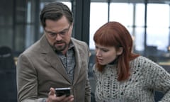Leonardo DiCaprio and Jennifer Lawrence staring at a phone in a scene from Don't Look Up
