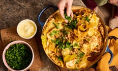 Overhead shot of a ovenproof dish with braised cabbage in a rich tomato sauce, being garnished with chopped green herbs.