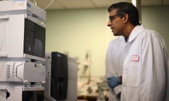 Rishi Sunak wearing a white lab coat looks at a vape testing machine.
