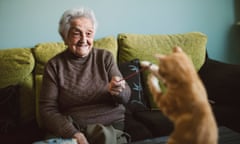 Smiling senior woman playing with her kitten at home<br>Happy elderly woman playing with her ginger kitten at home, Spain.