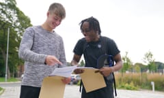 Two happy looking male students with results envelopes