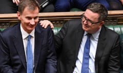 Jeremy Hunt and Mel Stride in the House of Commons last October, sitting together on the benches; Stride has his hand on Hunt's shoulder and is congratulating him after his autumn budget speech. Both wear dark suits with white shirts and blue ties.