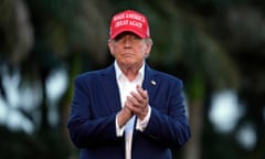 white man wearing blue suit and red hat clasps hands together