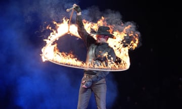 A man in black clothes and black stetson spins a blazing lasso around his body