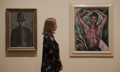 A Tate staff member poses for photographs next to "PC Harry Daley" by Duncan Grant, at left, and "Portrait of Pat Nelson" by Edward Wolfe during a media preview for the "Queer British Art 1861-1967" exhibition at Tate Britain in London, Monday, April 3, 2017. The show, which opens to the public on Wednesday, includes works that relate to lesbian, gay, bisexual, and trans queer identities and marks the 50th anniversary of the partial decriminalisation of male homosexuality in England and Wales. (AP Photo/Matt Dunham)