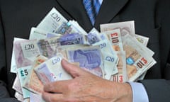 Businessman in suit and tie with hand holding stack sterling bank notes