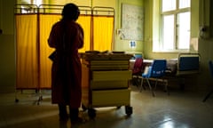 A nurse walks over to a supply cart to prepare treatments for patients.