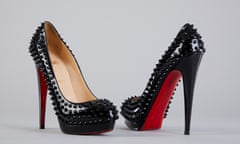 Black patent leather women's shoes with very high heels, bright red soles and aggressive studs all over the uppers