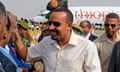 Abiy Ahmed, with close-cropped hair and in a short-sleeved shirt and sunglasses, grinning at Khartoum airport with men around him and a plane labelled "Ethiopia" behind them