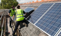 Workers install photovoltaic solar panels on the slate roof of a Victorian house in London