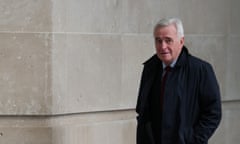 John McDonnell walks outside BBC Broadcasting House, November 2023 – he is wearing a black coat and is pictured against a stretch of plain, pale stone wall