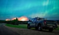 a wildfire burns beneath the aurora borealis