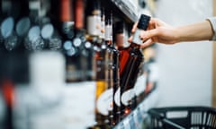 Close up of woman walking through liquor aisle and choosing a bottle of liquor from the shelf in a supermarket