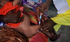 A baby is held while an injection goes into its leg