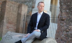 edward st aubyn sits for a photo outside near some ruins in rome