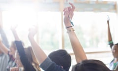 Teenage students with arms raised in classroom