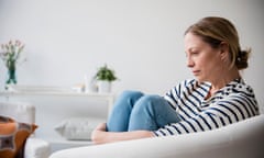 Caucasian woman sitting in armchair holding legs