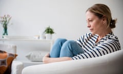 woman sitting in armchair holding legs