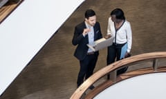 Business People Standing in the Middle of a Building's Corridor, Discussing and Using Laptop