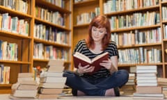 Student in pile of books in library