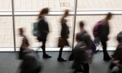 Secondary school pupils moving by a window in a school.