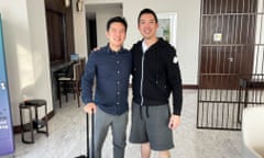 two men pose for picture, one with a suitcase