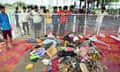 People stand behind a white metal fence looking at personal belongings piled on floor coverings