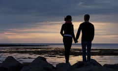 Couple holding hands looking at sunset